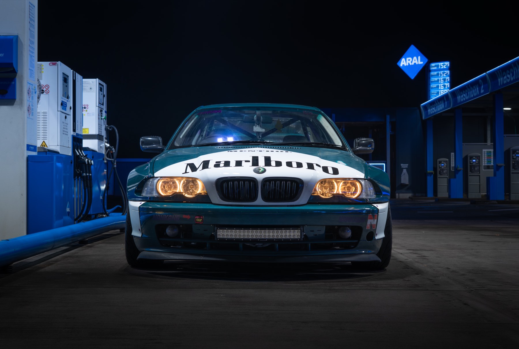 BMW E46 mit Breitbau nachts an einer Tankstelle