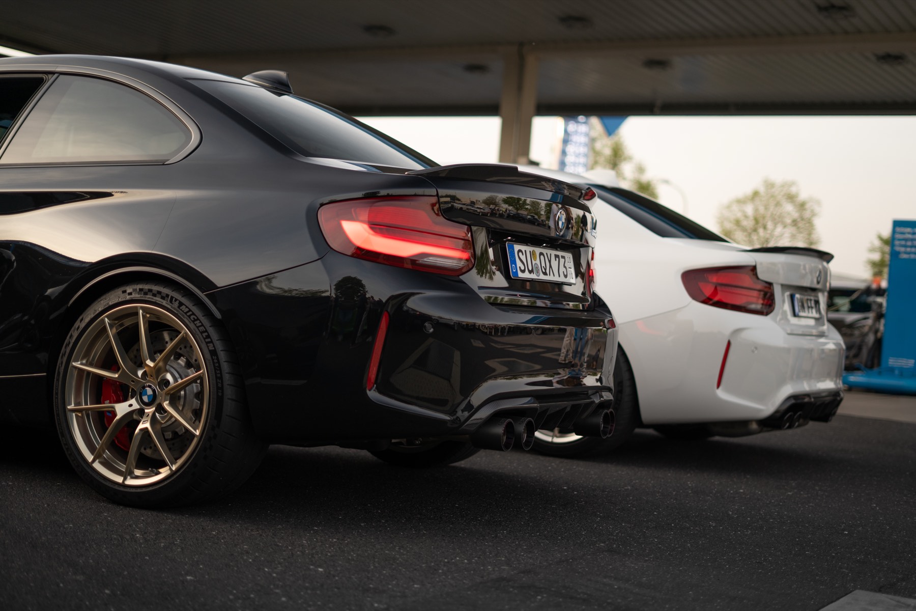 Schwarzer BMW M2 CS und weißer BMW M2 Competition an einer Tankstelle