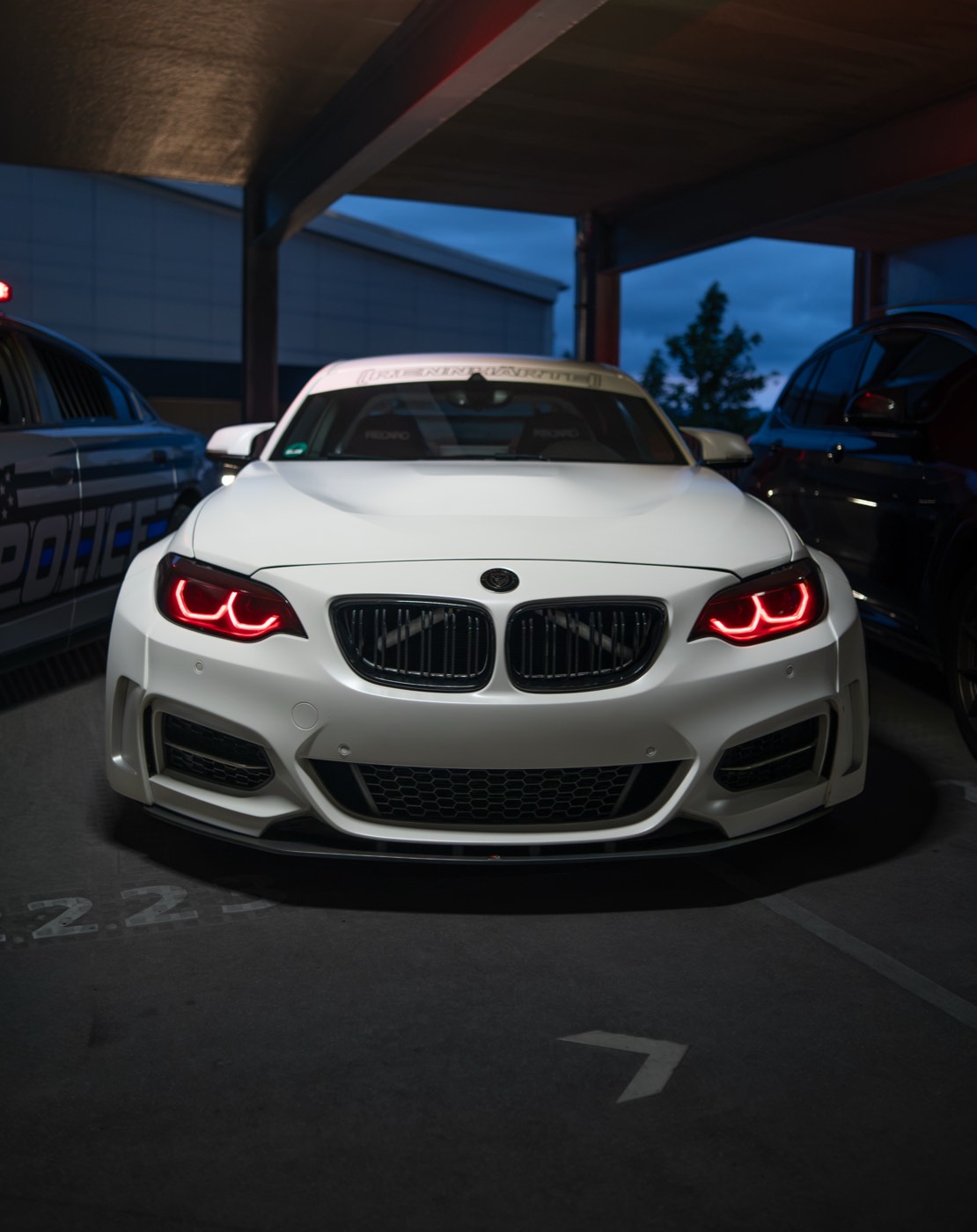 Weißer BMW M2 Rennwagen frontal in der Dämmerung
