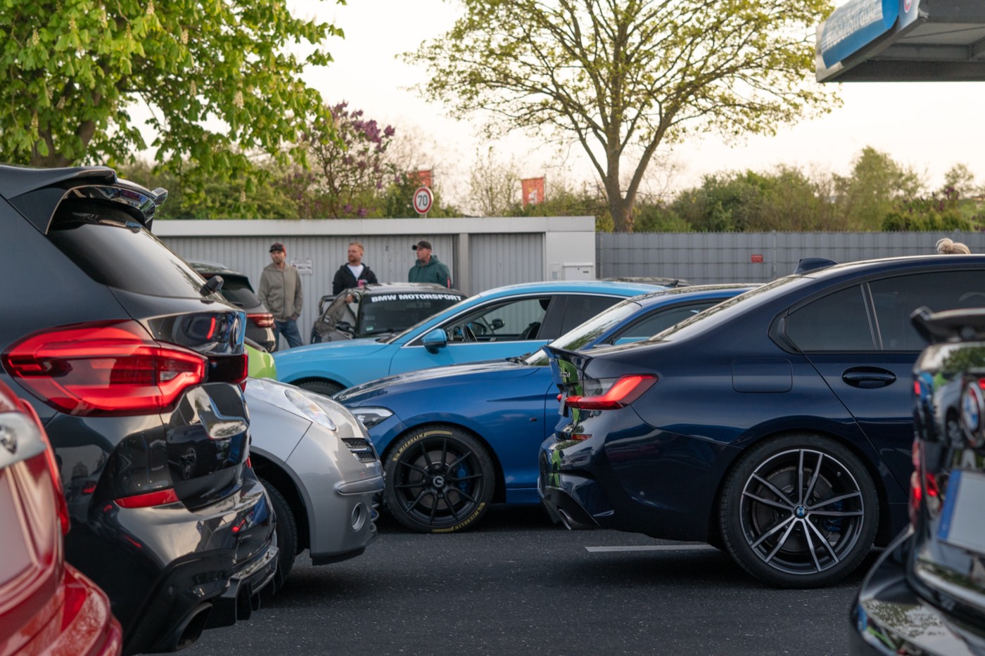 Fahrzeuge und Besucher auf dem Parkplatz eines Treffens